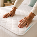 Hands smoothing a Confio Bed Pad onto a mattress